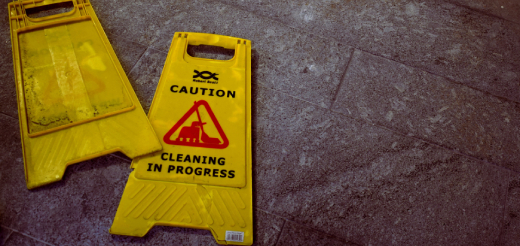 A yellow sign reading “caution, cleaning in progress” lying on a stone floor