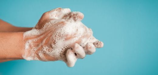 Hands covered in soap in front of blue background