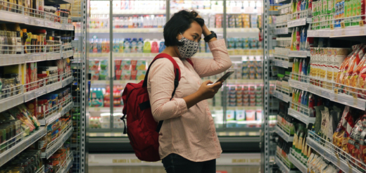 A person holds their head as they look through a grocery store aisle