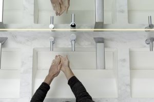 Person washing hands at D|13 sink system featuring the XLERATORsync hand dryer